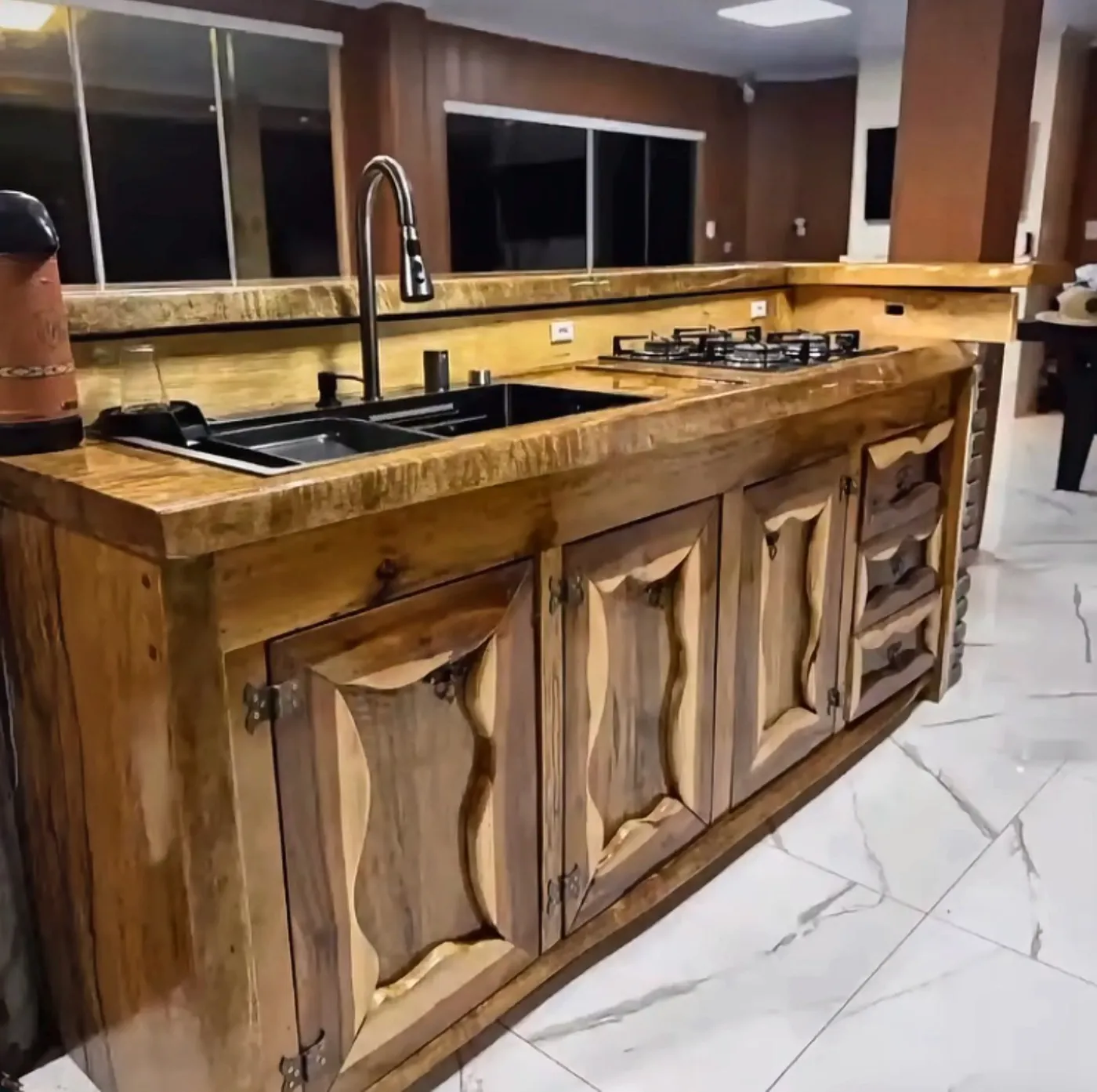 Cozinha sob medida com bancada e portas em madeira maciça de recortes orgânicos